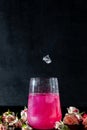 A sparkling brilliant raspberry drink in a glass stands on a wooden table with ice. In the background are roses and a garland Royalty Free Stock Photo