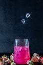 A sparkling brilliant raspberry drink in a glass stands on a wooden table with ice. In the background are roses and a garland Royalty Free Stock Photo