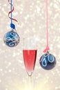 Sparkling champagne and two hanging baubles against Christmas li Royalty Free Stock Photo