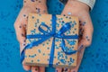 Sparkling Gift box wrapped in craft paper and tied with bow in Kid`s hands