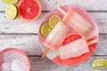 Lime and grapefruit ice pops, top view table scene over white wood