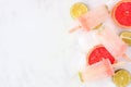 Lime and grapefruit popsicles, top view side border on a marble background Royalty Free Stock Photo