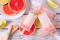 Lime and grapefruit popsicles, top view table scene over white wood