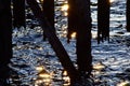 Sparkling sun reflection on waves under old weathered wooden pier