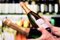 Sparkling wine in alcohol store. Champagne or prosecco in liquor shop. Man holding two bottles in hands, choosing drink.