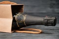 Sparkling wine in craft gift bag on black wooden background