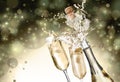 Sparkling wine splashing out of bottle and glasses on color background, bokeh effect Royalty Free Stock Photo