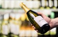 Sparkling wine in supermarket or alcohol store. Man holding bottle of champagne or prosecco in liquor shop. Royalty Free Stock Photo