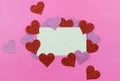 Sparkly pink and red hearts surround a parchment paper tage on a bright pink background for Valentine`s Day in February. Copy spa