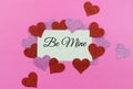 Sparkly pink and red hearts surround a parchment paper tage on a bright pink background for Valentine`s Day in February. Message