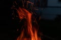 Sparks and flame erupt from the top of a chimney starter fire on a backyard grill