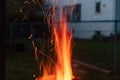 Sparks and flame erupt from the top of a chimney starter fire on a backyard grill