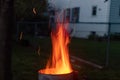 Sparks and flame erupt from the top of a chimney starter fire on a backyard grill