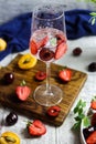 Sparlking wine with berries. Refreshing cooling sparkling summer drink with fresh strawberry, cherry and ice cubes. Prosecco Royalty Free Stock Photo