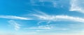 Sparse translucent cirrus clouds high in the clear blue sky. Wide panorama of azure heaven with white rarefied clouds on a sunny Royalty Free Stock Photo