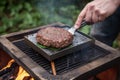 spatula flipping juicy burger on portable grill