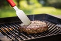 spatula flipping an oversized burger patty on a grilling pan