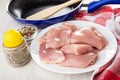 Spatula in frying pan, bowl with condiment, pepper, white plate with pieces of chicken meat, napkin on wooden table Royalty Free Stock Photo