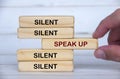 Speak up and silent text on wooden block with hand pulling the wooden block with speak up text. Speak up and courage concept Royalty Free Stock Photo
