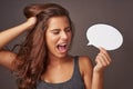 Speak your truth...or shout it. Studio shot of an attractive young woman holding a blank speech bubble and shouting