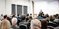 Speaker giving a talk in conference hall at business event. Rear view of unrecognizable people in audience at the Royalty Free Stock Photo