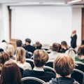 Speaker giving a talk in conference hall at business event. Rear view of unrecognizable people in audience at the Royalty Free Stock Photo