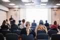 Speaker giving a talk in conference hall at business event. Rear view of unrecognizable people in audience at the Royalty Free Stock Photo