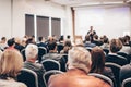 Speaker giving a talk in conference hall at business event. Rear view of unrecognizable people in audience at the Royalty Free Stock Photo