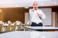 The speaker held the microphone in his hand and show his forefinger to the listener  with blurry conference room and projector Royalty Free Stock Photo