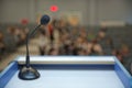 Speaker prepare before speaking to the audience behind the podium focused microphone on the podium and blurred empty seat and some