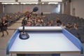 Speaker prepare before speaking to the audience behind the podium focused microphone on the podium and blurred empty seat and some