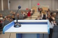 Speaker prepare before speaking to the audience behind the podium focused microphone on the podium and blurred empty seat and some