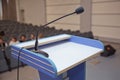 Speaker prepare before speaking to the audience behind the podium focused microphone on the podium and blurred empty seat and some