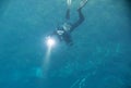 Spearfishing man with flashlight in deep of lake