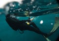 Spearfishing man with flashlight in deep of lake swimming with action camera near water surface