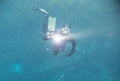 Spearfishing man with flashlight in deep of lake swimming with action camera