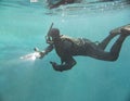 Spearfishing man in mask with flashlight in lake