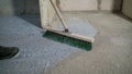 With a special brush, level the primer on the floor. The process of priming concrete floors