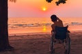 Special child on wheelchair on the sea beach with sunset on travel time Royalty Free Stock Photo