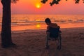 Special child on wheelchair on the sea beach with sunset on travel time Royalty Free Stock Photo