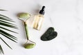 Special devices for Gua Sha. Jade face roller, stone for massage and essential oil on marble table.Traditional Chinese