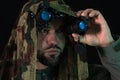 A special forces soldier in a camouflage net and modern night vision goggles, looking through the device during a nighttime Royalty Free Stock Photo