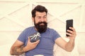 Special gift. Bearded man using mobile technology in bed. Handsome guy taking selfie with gift box. Happy selfie. Modern Royalty Free Stock Photo