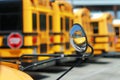 A special needs school bus` reflection in its own mirror with the big ones in the background.