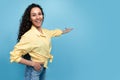 Special offer, advertisement concept. Joyful millennial woman pointing at empty space on blue studio background