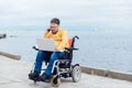 a special person with disabilities by the sea with a laptop Royalty Free Stock Photo