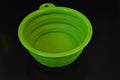 Green folding and multifunctional rubber plate, a bowl with a plastic edging on a black glossy surface.