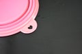 Pink folding and multifunctional rubber plate, a bowl with a plastic edging on a black glossy surface.