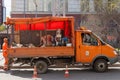 A special truck with orange road work equipment and workers in yellow uniforms with old cones nearby on the asphalt.