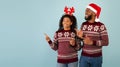Special xmas offer. Happy black couple pointing aside at copy space for your advertisement over blue background